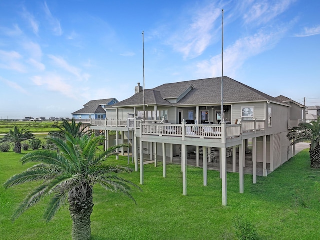 back of house with roof with shingles, a lawn, and a wooden deck