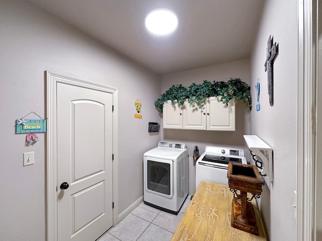 clothes washing area featuring washing machine and clothes dryer, light tile patterned flooring, baseboards, and cabinet space