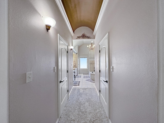 hall featuring ornamental molding, an inviting chandelier, lofted ceiling, and light colored carpet