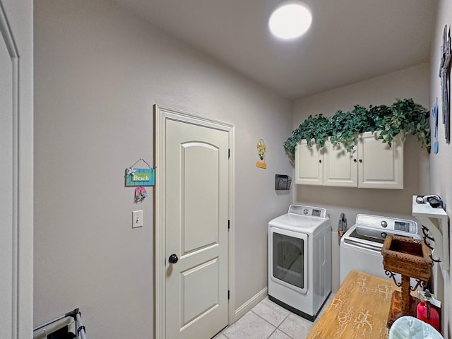 clothes washing area with light tile patterned flooring, cabinet space, and washer and dryer