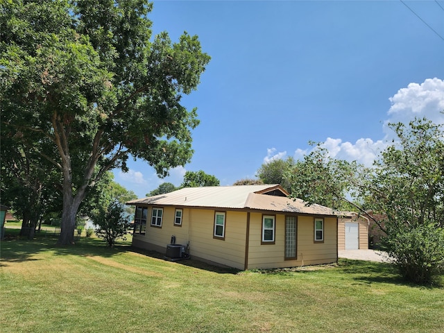 rear view of house featuring central AC and a lawn