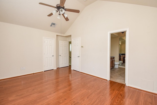 unfurnished bedroom featuring connected bathroom, wood-type flooring, high vaulted ceiling, and ceiling fan