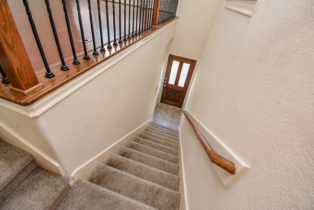 staircase featuring a high ceiling and carpet flooring