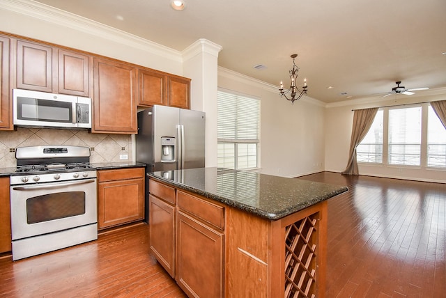 kitchen with ornamental molding, a kitchen island, hardwood / wood-style flooring, stainless steel appliances, and decorative backsplash