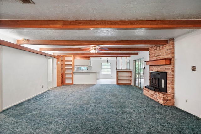 unfurnished living room with ceiling fan, a textured ceiling, beamed ceiling, and carpet