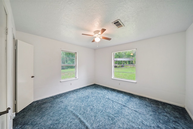 unfurnished room with ceiling fan, a textured ceiling, and dark colored carpet