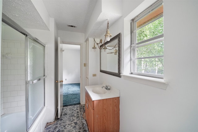 bathroom with vanity, shower / bath combination with glass door, and a textured ceiling