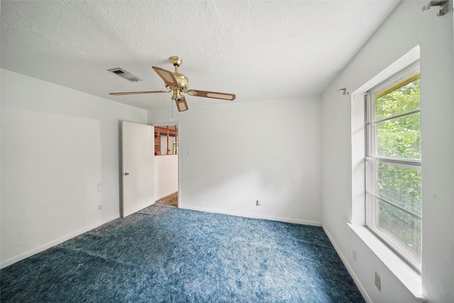 carpeted empty room with ceiling fan and a textured ceiling