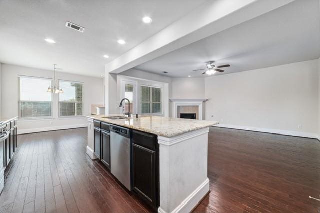 kitchen with dishwasher, sink, pendant lighting, a center island with sink, and ceiling fan with notable chandelier