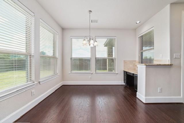 unfurnished dining area with a chandelier, dark hardwood / wood-style flooring, and a healthy amount of sunlight