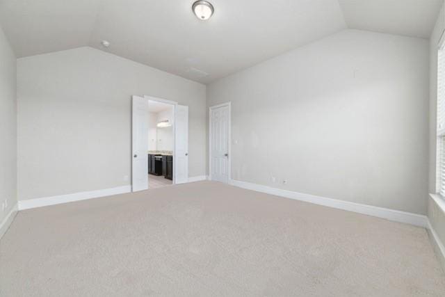 unfurnished room featuring light colored carpet and lofted ceiling