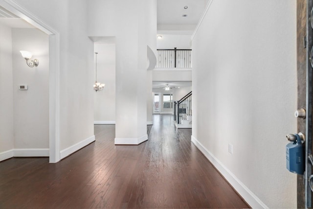 entryway featuring a notable chandelier, a towering ceiling, and dark wood-type flooring