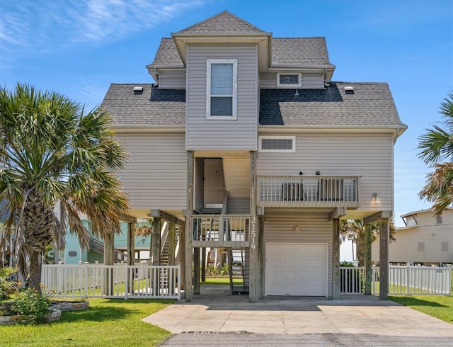 beach home with a front yard, a balcony, and a garage