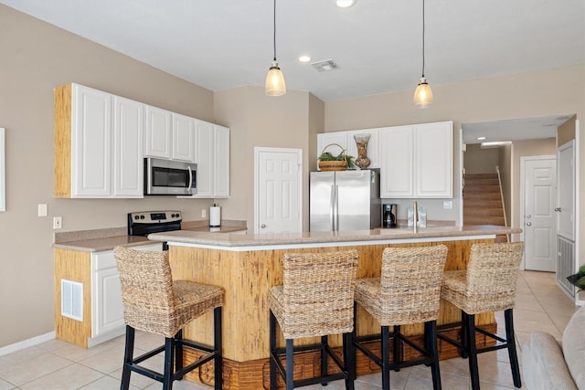 kitchen with light tile patterned floors, stainless steel appliances, white cabinetry, and a kitchen island with sink