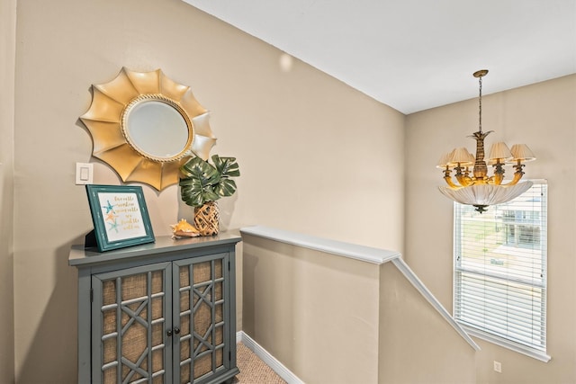 hallway featuring a notable chandelier, plenty of natural light, and carpet flooring