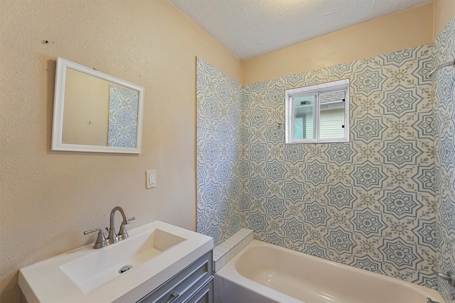 bathroom featuring tiled shower / bath, vanity, and a textured ceiling