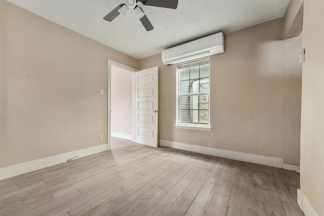 unfurnished room featuring light wood-type flooring, a wall mounted AC, and ceiling fan