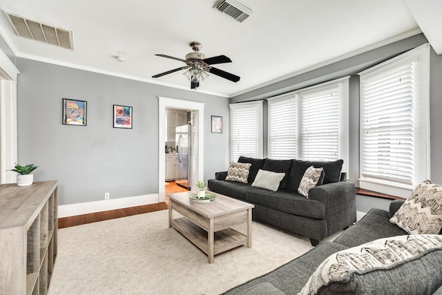 living room with ornamental molding, ceiling fan, and light wood-type flooring