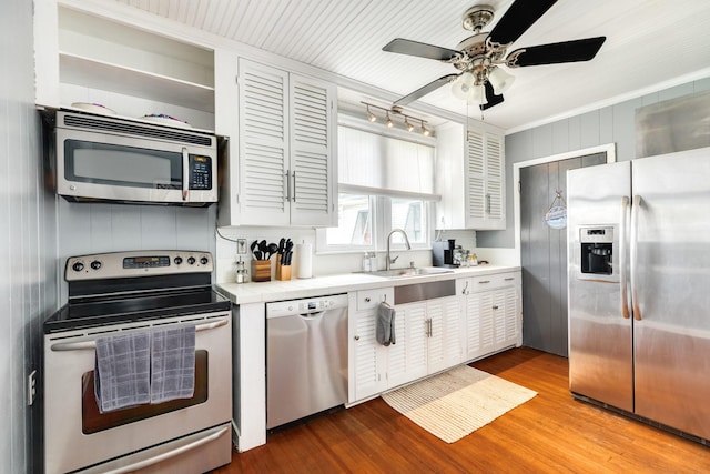 kitchen with appliances with stainless steel finishes, white cabinetry, sink, ceiling fan, and light hardwood / wood-style floors