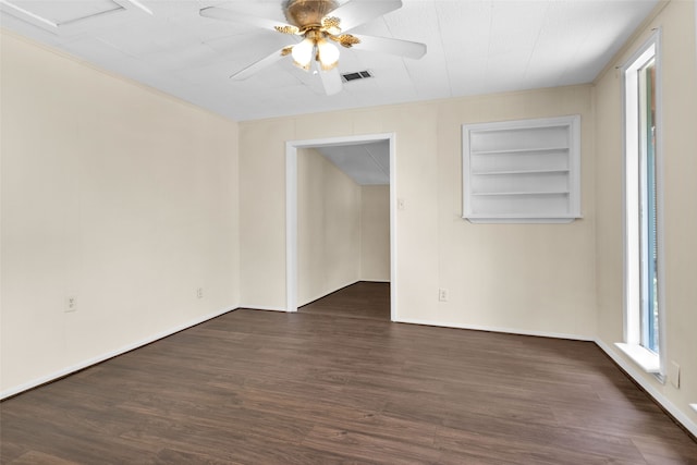 empty room with ceiling fan, dark hardwood / wood-style floors, and built in shelves