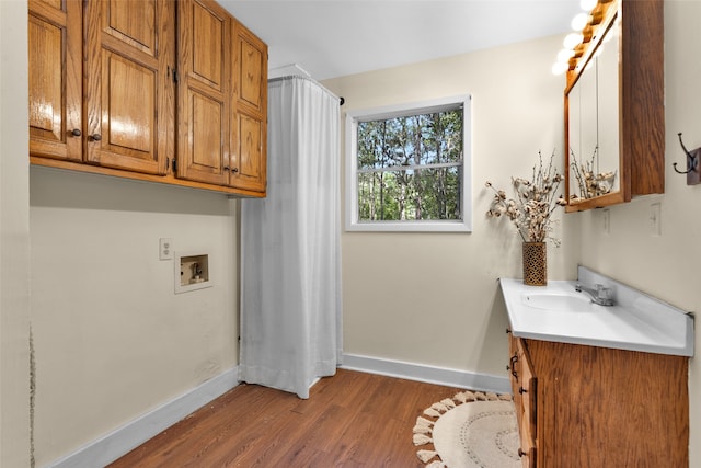 clothes washing area featuring dark wood-type flooring, washer hookup, cabinets, and sink