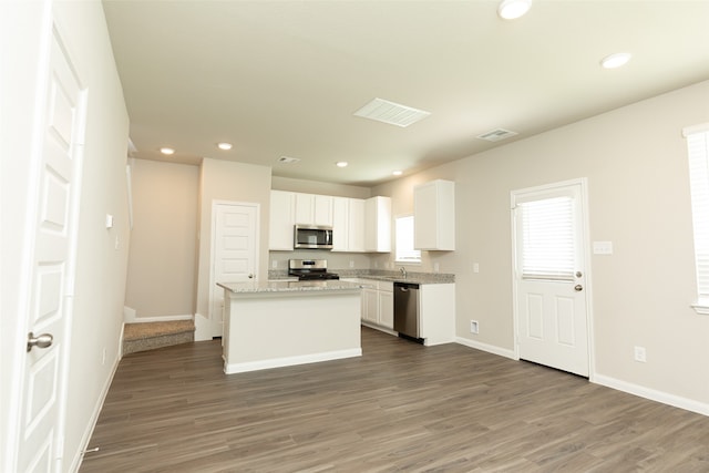 kitchen featuring light stone counters, a center island, dark wood-type flooring, white cabinets, and stainless steel appliances