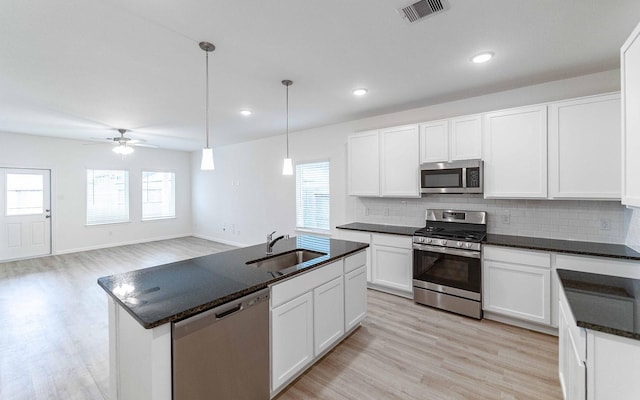 kitchen with sink, stainless steel appliances, pendant lighting, and white cabinets