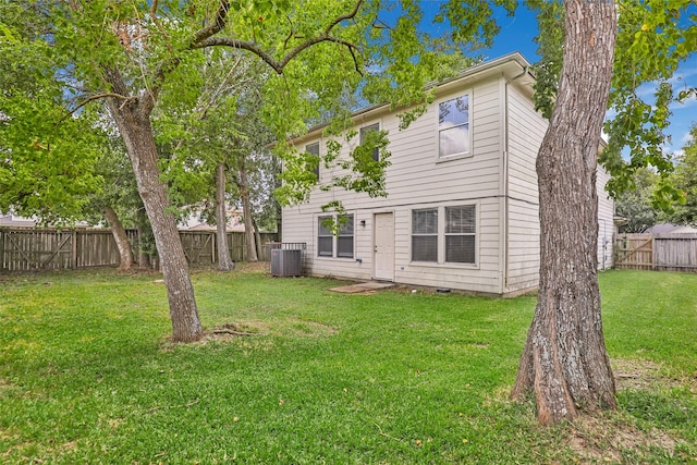 rear view of house with cooling unit and a lawn