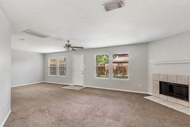 unfurnished living room featuring ceiling fan, light carpet, a tile fireplace, and a wealth of natural light