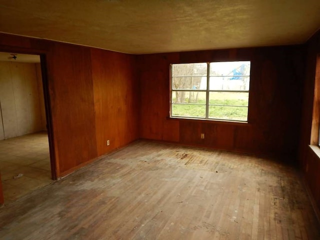 unfurnished room with wood walls and light hardwood / wood-style floors