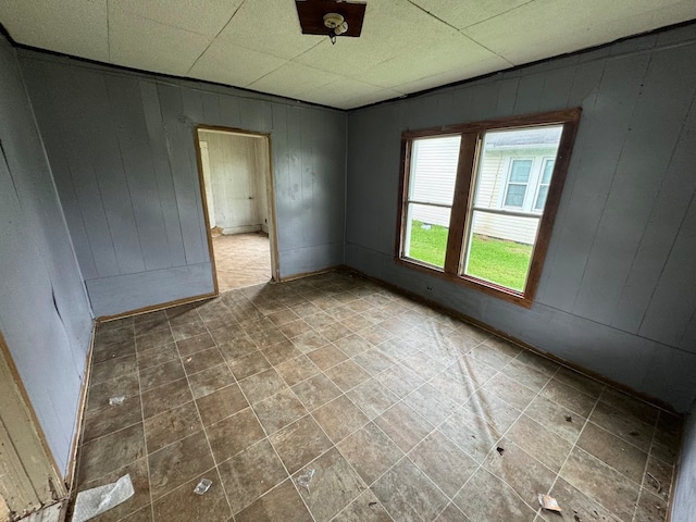 tiled empty room featuring a drop ceiling