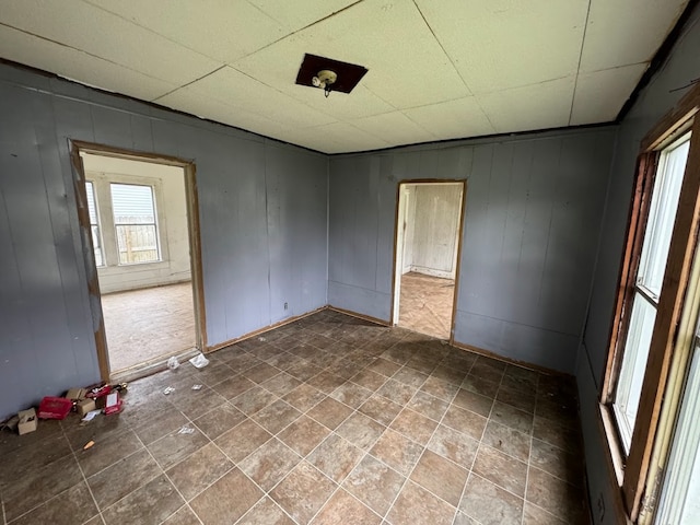 spare room featuring a drop ceiling and tile patterned floors