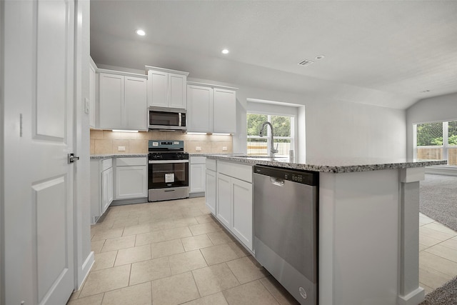 kitchen featuring backsplash, a center island, sink, white cabinetry, and stainless steel appliances