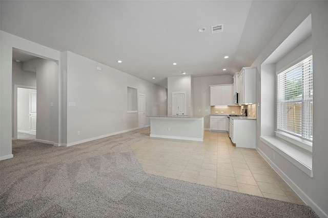 unfurnished living room featuring light colored carpet and sink