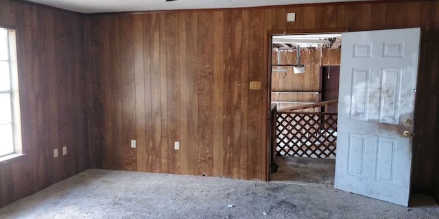 carpeted spare room featuring wood walls