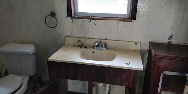 bathroom featuring vanity, tile walls, and toilet