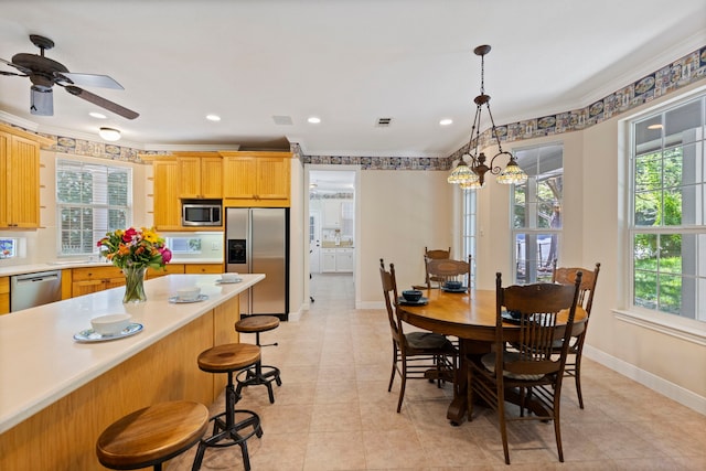 tiled dining area with ceiling fan with notable chandelier and crown molding