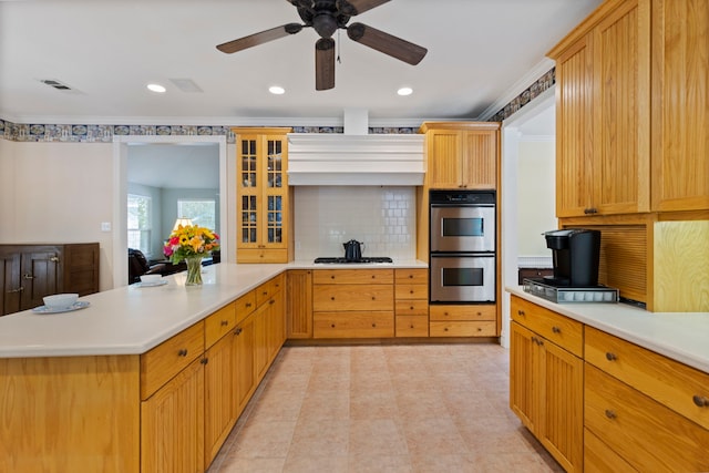 kitchen with backsplash, gas stovetop, double oven, and ceiling fan