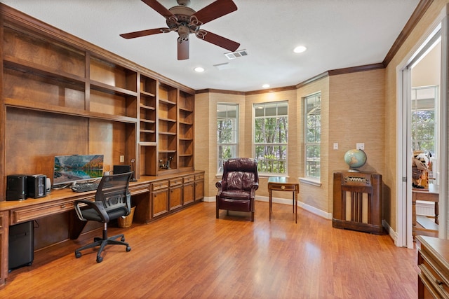 office area with a healthy amount of sunlight, built in desk, crown molding, and light hardwood / wood-style flooring