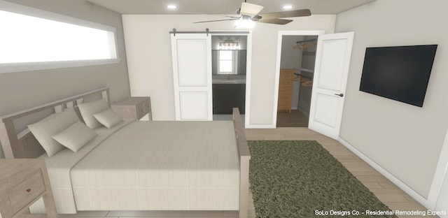 bedroom featuring ensuite bath, ceiling fan, a barn door, a spacious closet, and light hardwood / wood-style floors