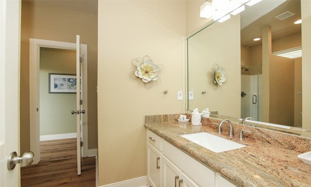 bathroom with hardwood / wood-style flooring, vanity, and a shower with door