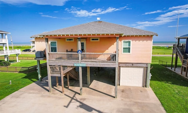 rear view of house featuring a garage, a water view, a yard, cooling unit, and covered porch