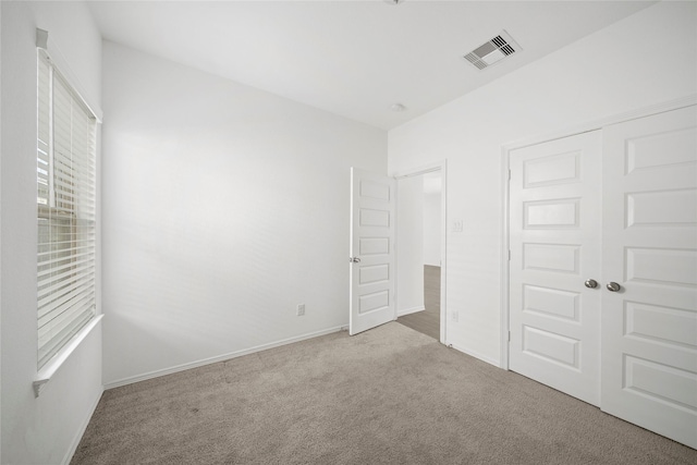 unfurnished bedroom with light colored carpet and a closet