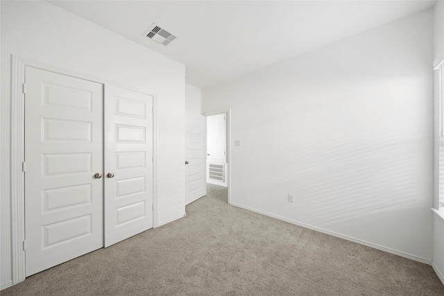 unfurnished bedroom with light colored carpet and a closet