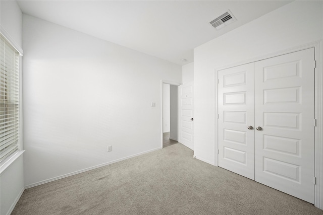 unfurnished bedroom featuring light carpet and a closet