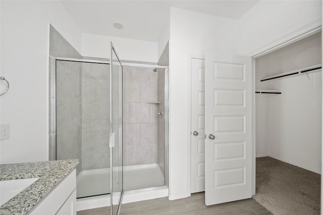 bathroom featuring a shower with shower door and vanity