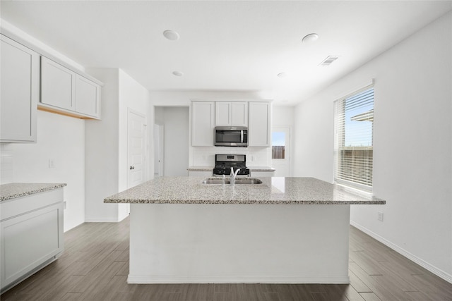 kitchen with white cabinetry, stainless steel appliances, a center island with sink, and sink