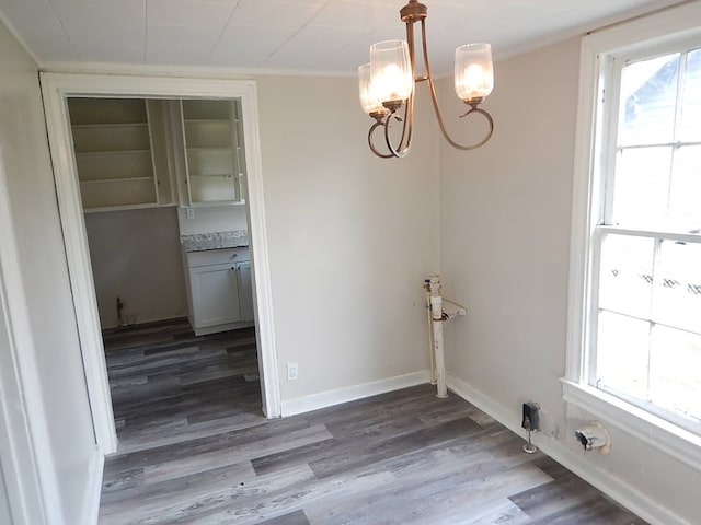 unfurnished dining area featuring ornamental molding, wood-type flooring, and a notable chandelier