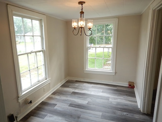 unfurnished dining area featuring an inviting chandelier, dark hardwood / wood-style flooring, and a wealth of natural light