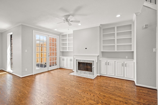 unfurnished living room with ceiling fan, built in features, a high end fireplace, hardwood / wood-style floors, and ornamental molding